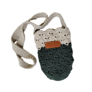 Handmade crochet crossbody bag with beige upper and dark green lower half, featuring a textured shell stitch pattern and a wide crochet strap.