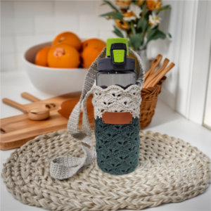 Handmade crochet crossbody bag with beige upper and dark green lower half, featuring a textured shell stitch pattern and a wide crochet strap