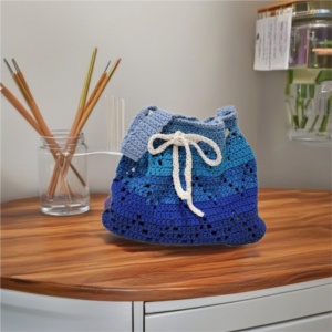 Handmade crochet zig zag shoulder bag in blue gradient tones with white drawstring.