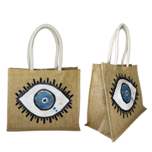 A jute tote bag featuring a hand-painted eye design on both sides, with black eyelashes surrounding a blue and white eye, and sturdy white handles.