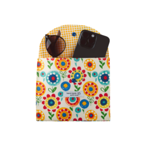 Floral fabric pouch with yellow gingham interior holding sunglasses and a black smartphone.