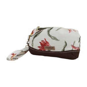 A handmade cosmetic pouch with a floral print, featuring a brown leather bottom and wrist strap, and a "hand made with love" label.