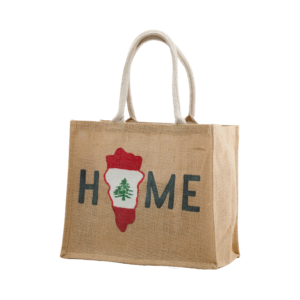 A jute tote bag with the word "HOME" printed on it, where the "O" is replaced by a red and white shape with a green cedar tree, symbolizing Lebanon.